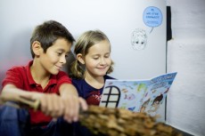 Zwei Kinder sitzen nebeneinander und schauen gemeinsam in einen Comic