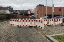 An einer gepflasterten Straße stehen viele rot-weiß gestreifte Warnschilder.