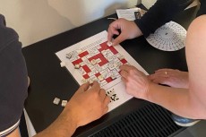 Mehrere Personen arbeiten gemeinsam an einem Rätsel mit Mosaiksteinen.